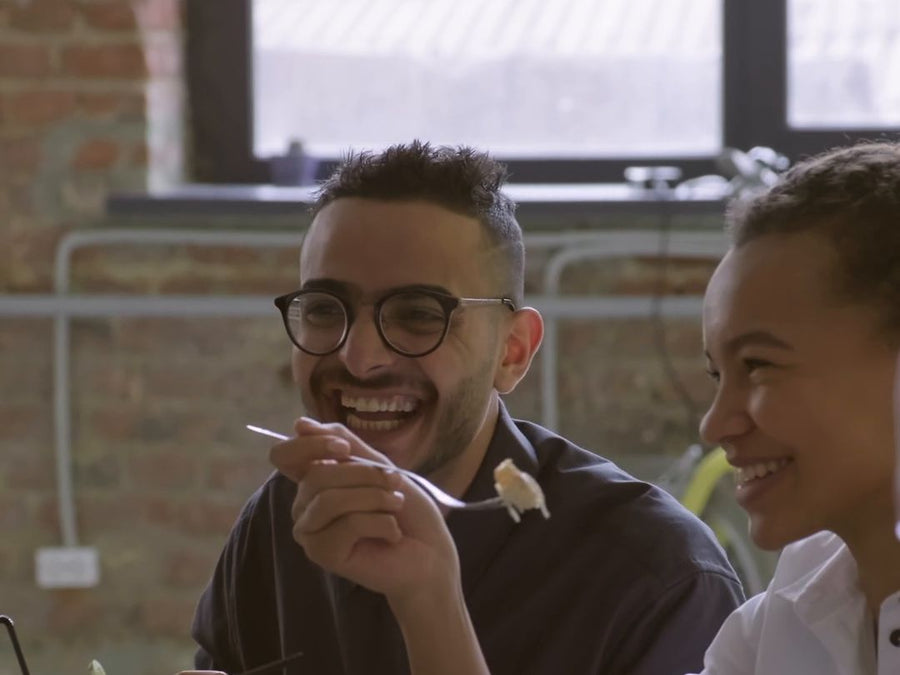 Amigos riendo mientras almuerzan juntos